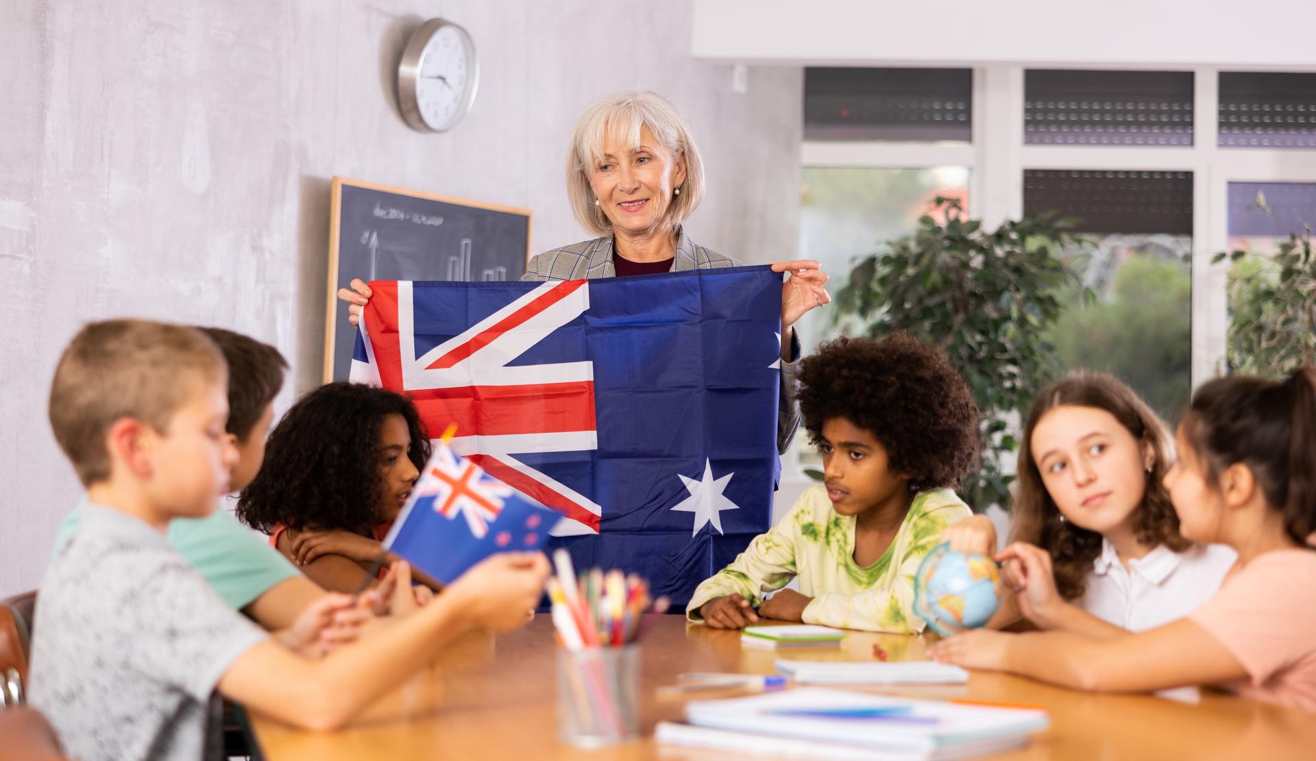 students  listen to woman teacher who talks about Australia